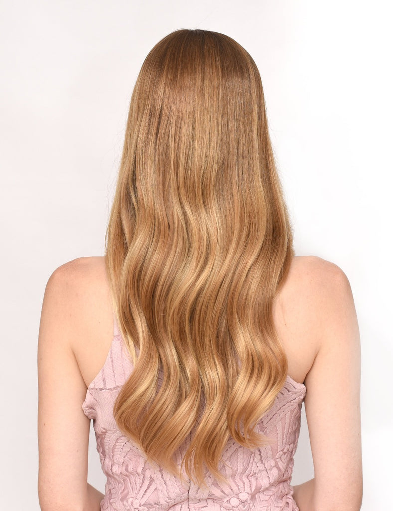 Back of model with silky, softy wavy blond hair after using hair heat protectant